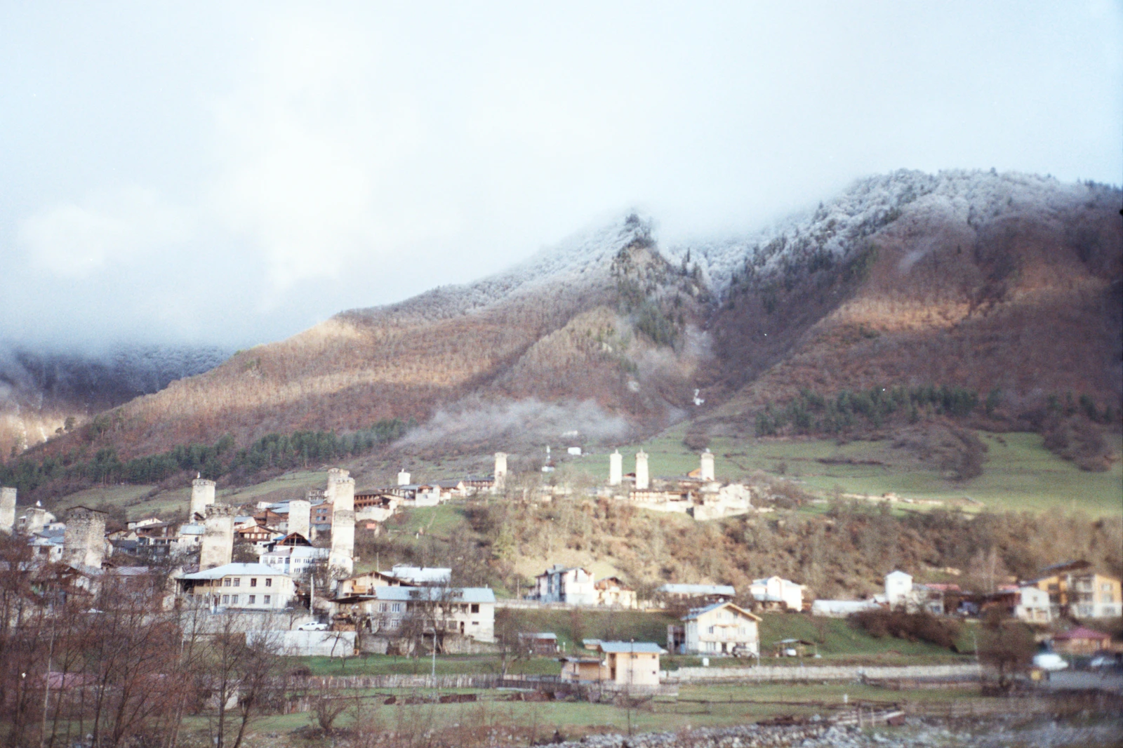 The stone Svan towers of Mestia under a cloud-covered mountain