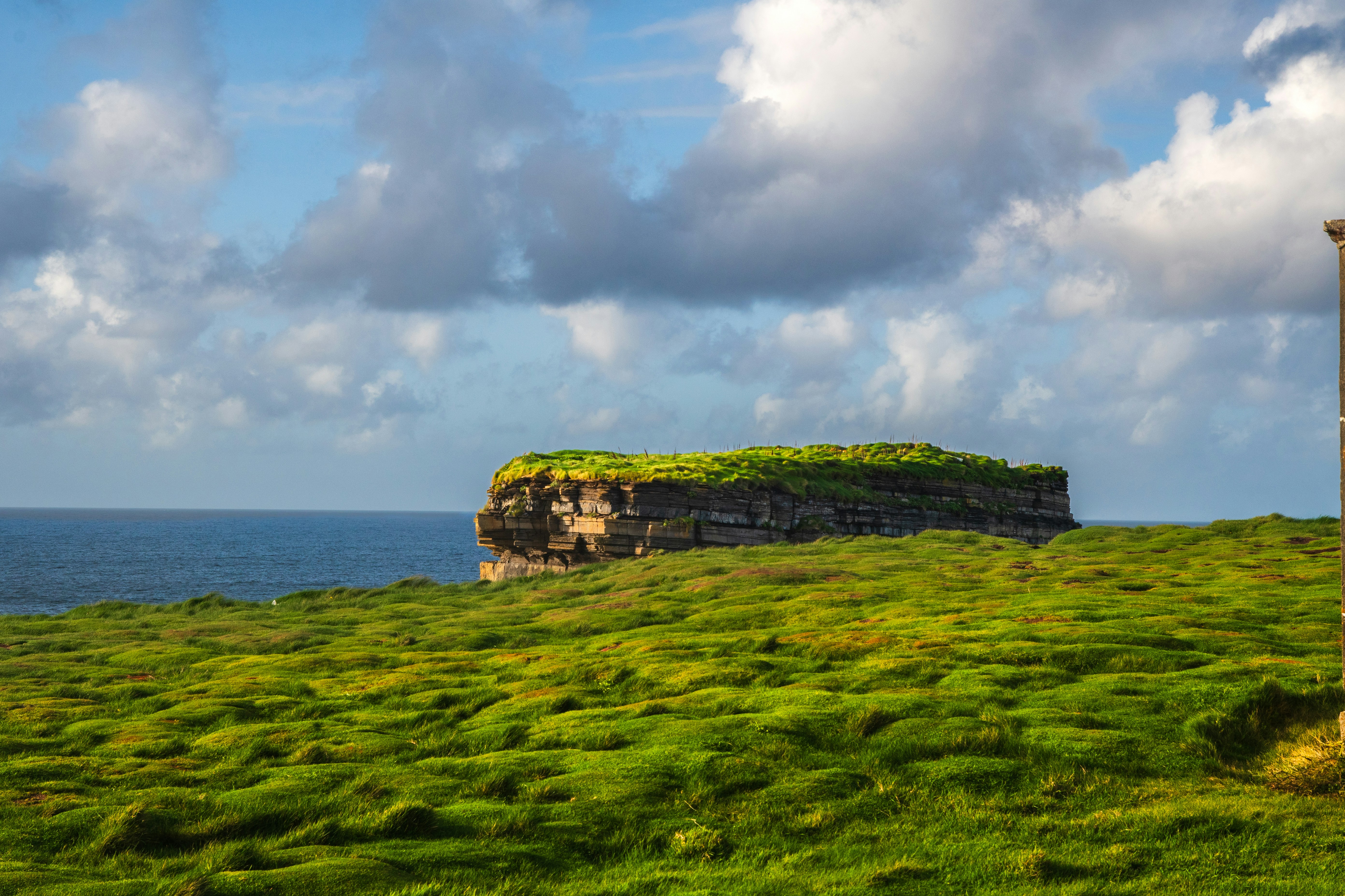 A grassy field with a small tower on top of it