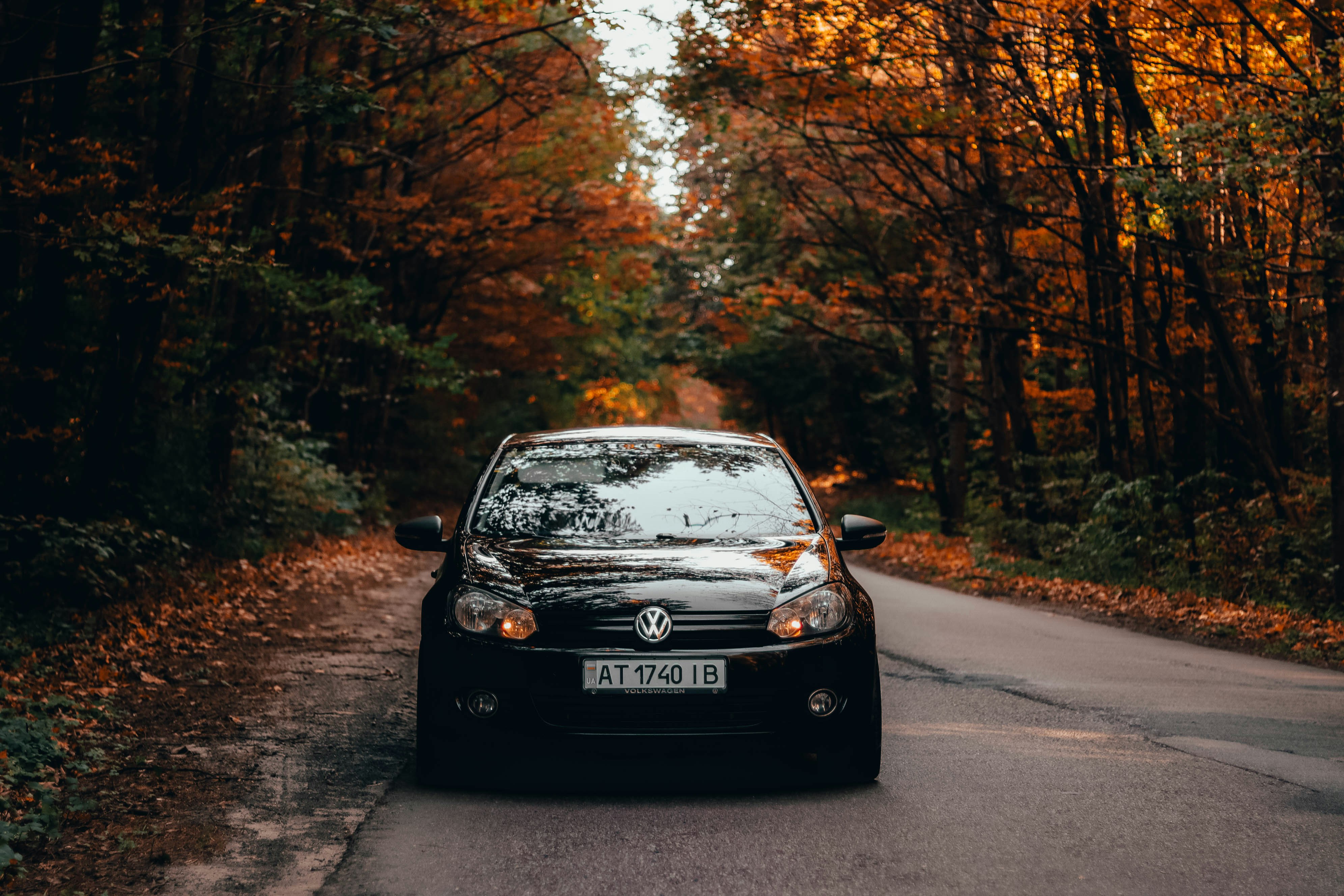 A black car driving down a road surrounded by trees