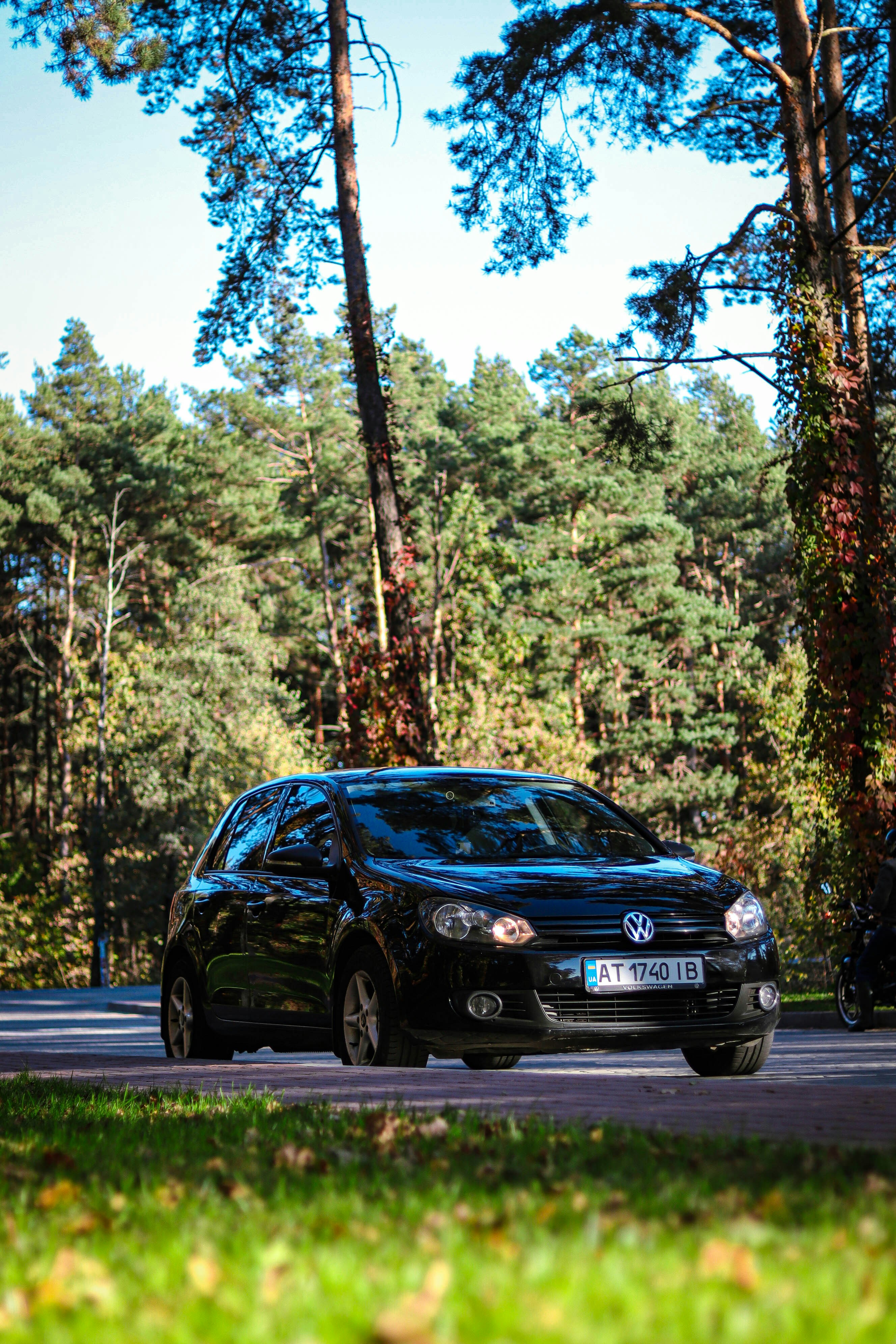 A black car driving down a street next to a forest