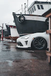 A white sports car parked in front of a boat