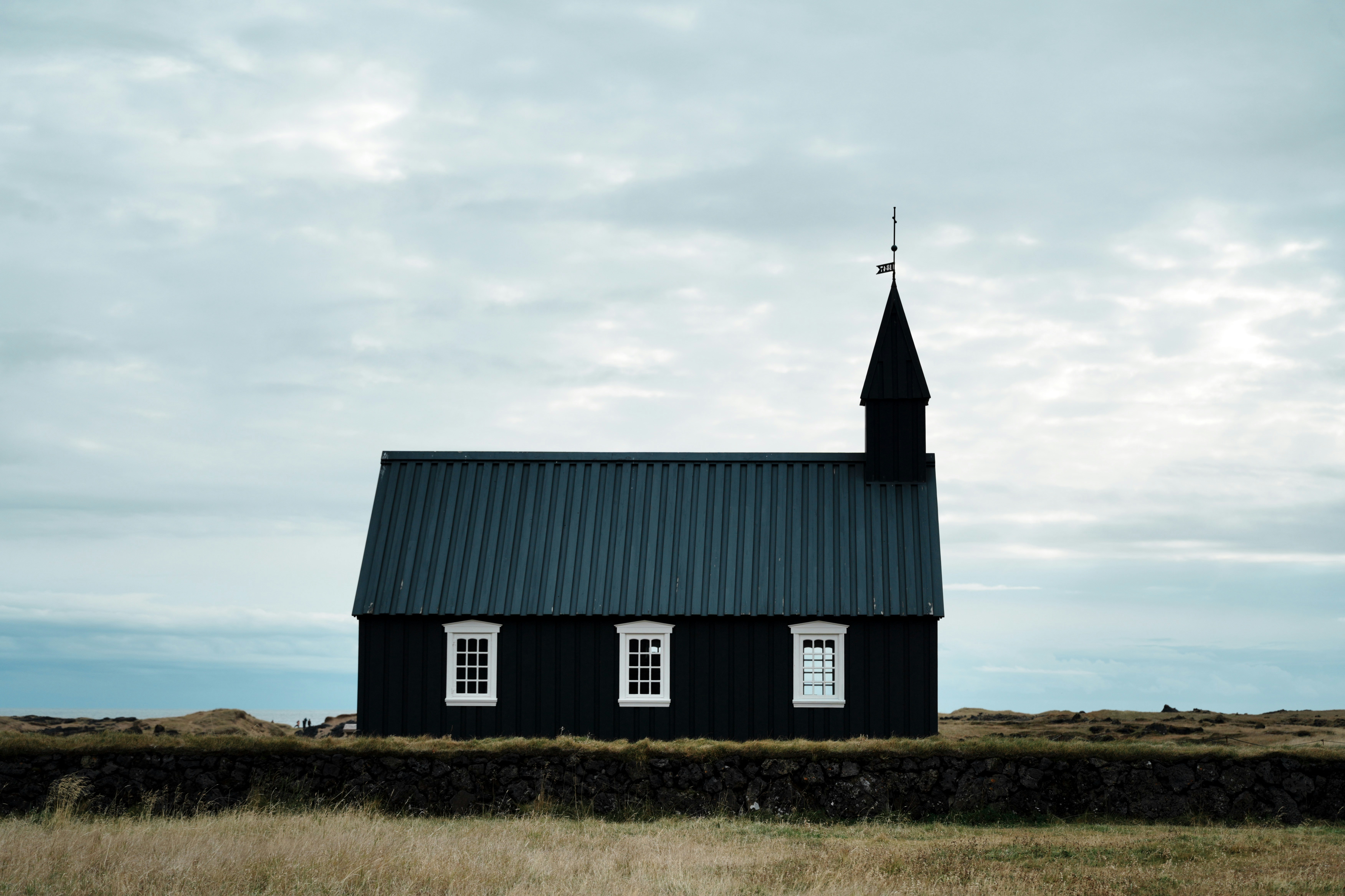 A small black church with a steeple on a hill
