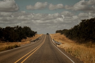 A long empty road with a fence in the middle of it