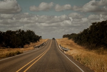 A long empty road with a fence in the middle of it