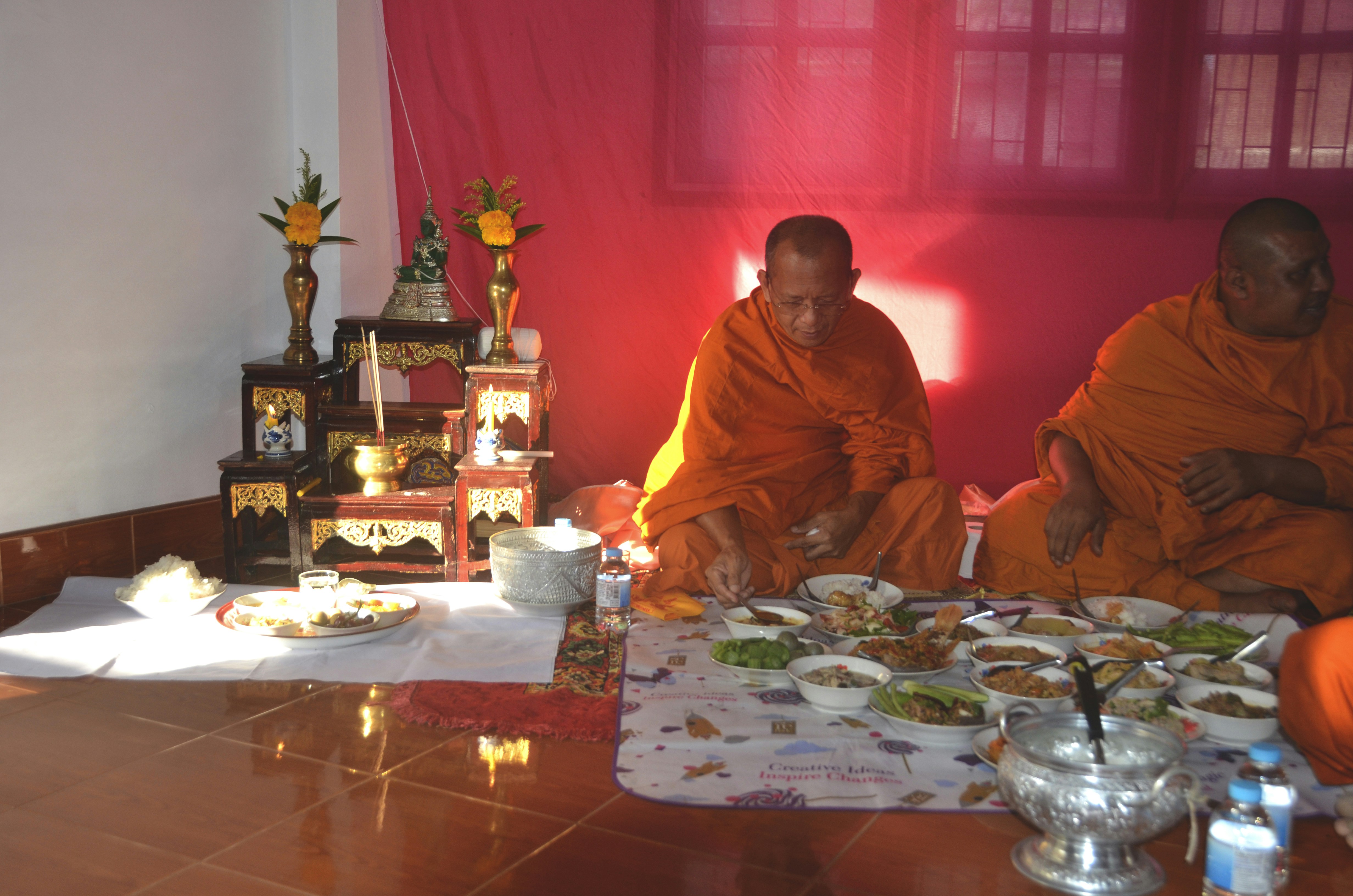 A group of monks sitting around a table eating food