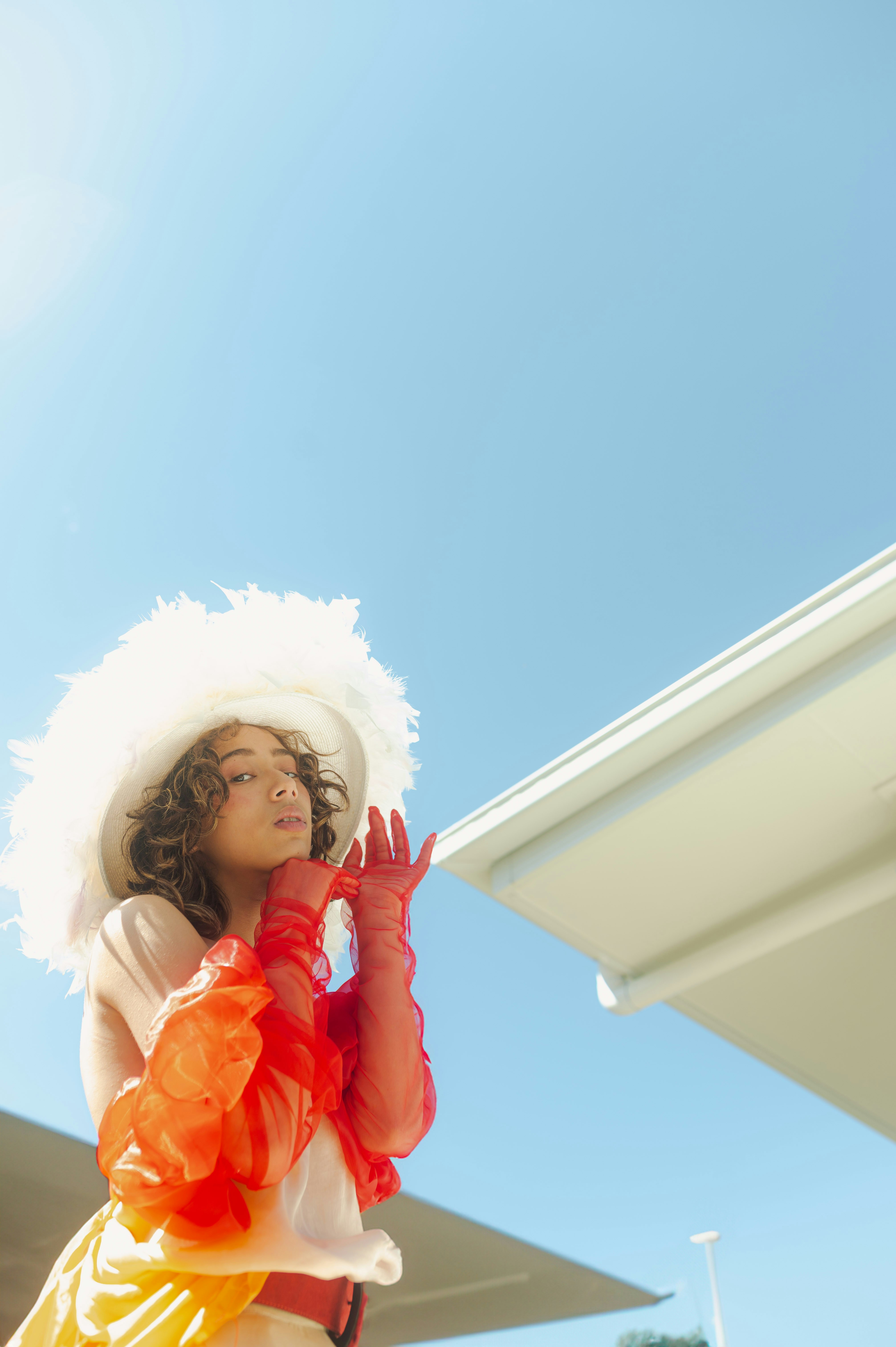 A woman wearing a white hat and orange and yellow dress