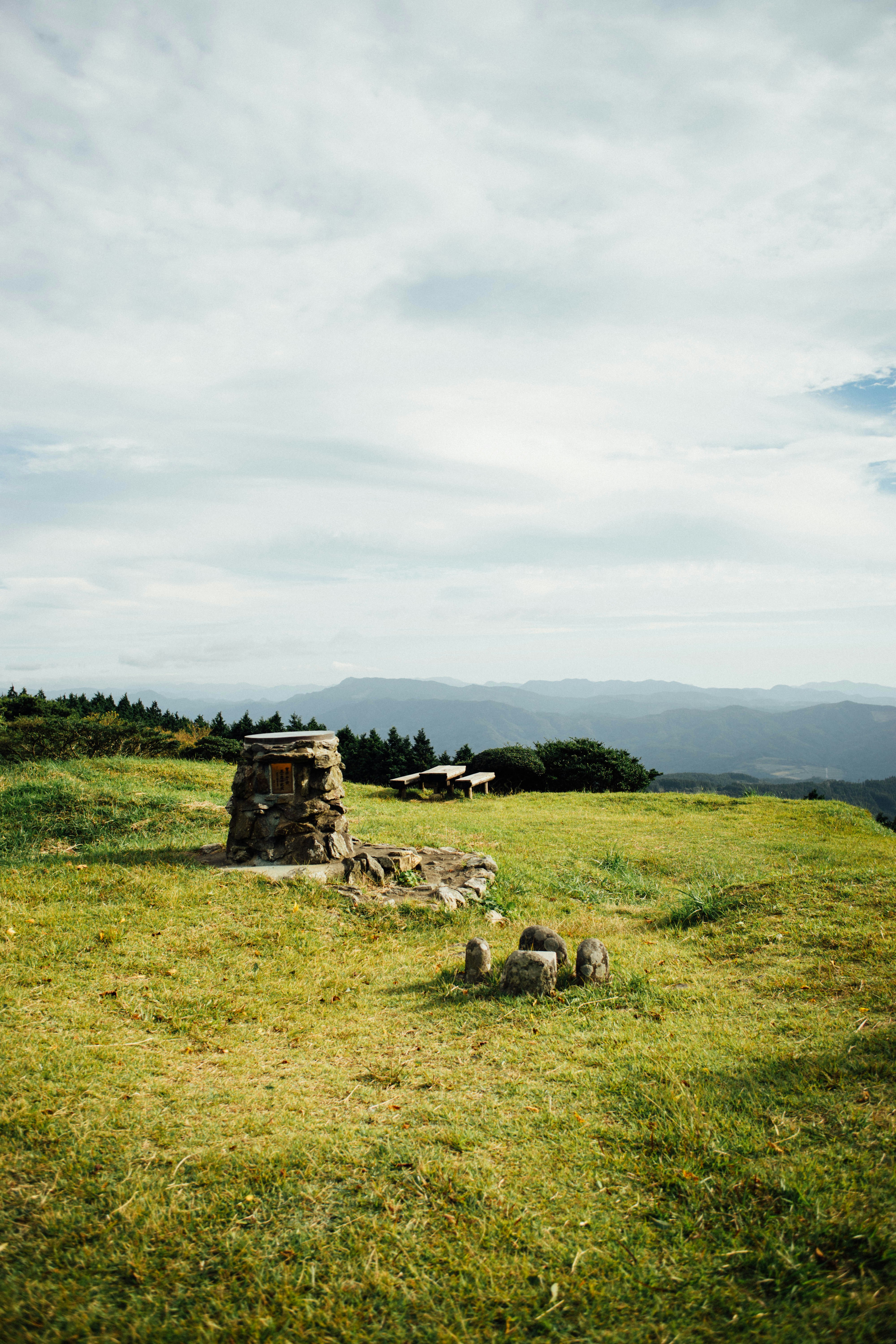 A grassy field with a stone structure in the middle of it