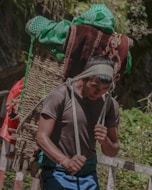 A man carrying a large bundle of luggage on his back