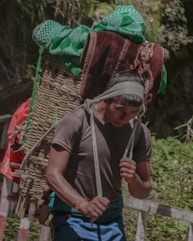 A man carrying a large bundle of luggage on his back