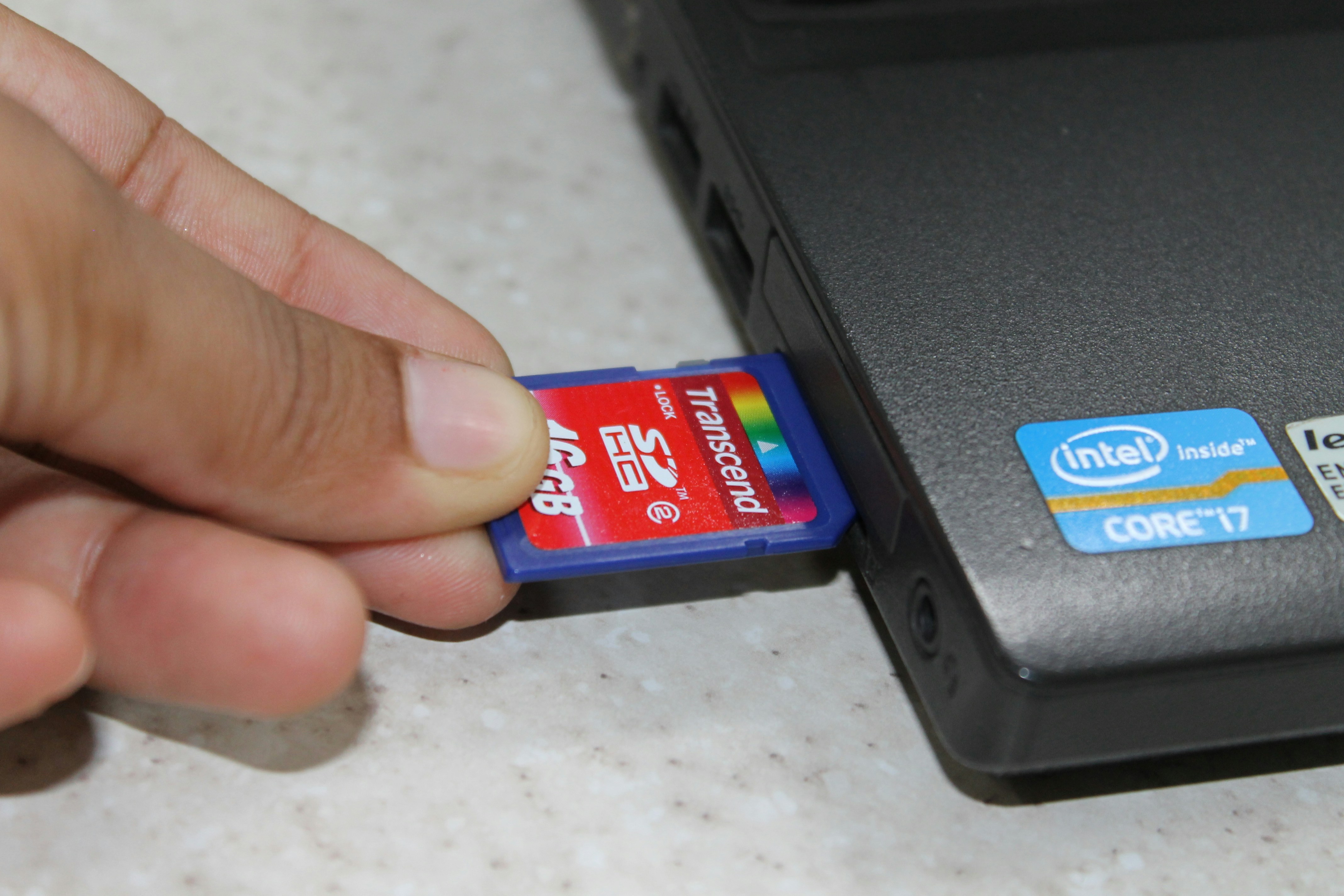 A hand is holding a small card near a laptop