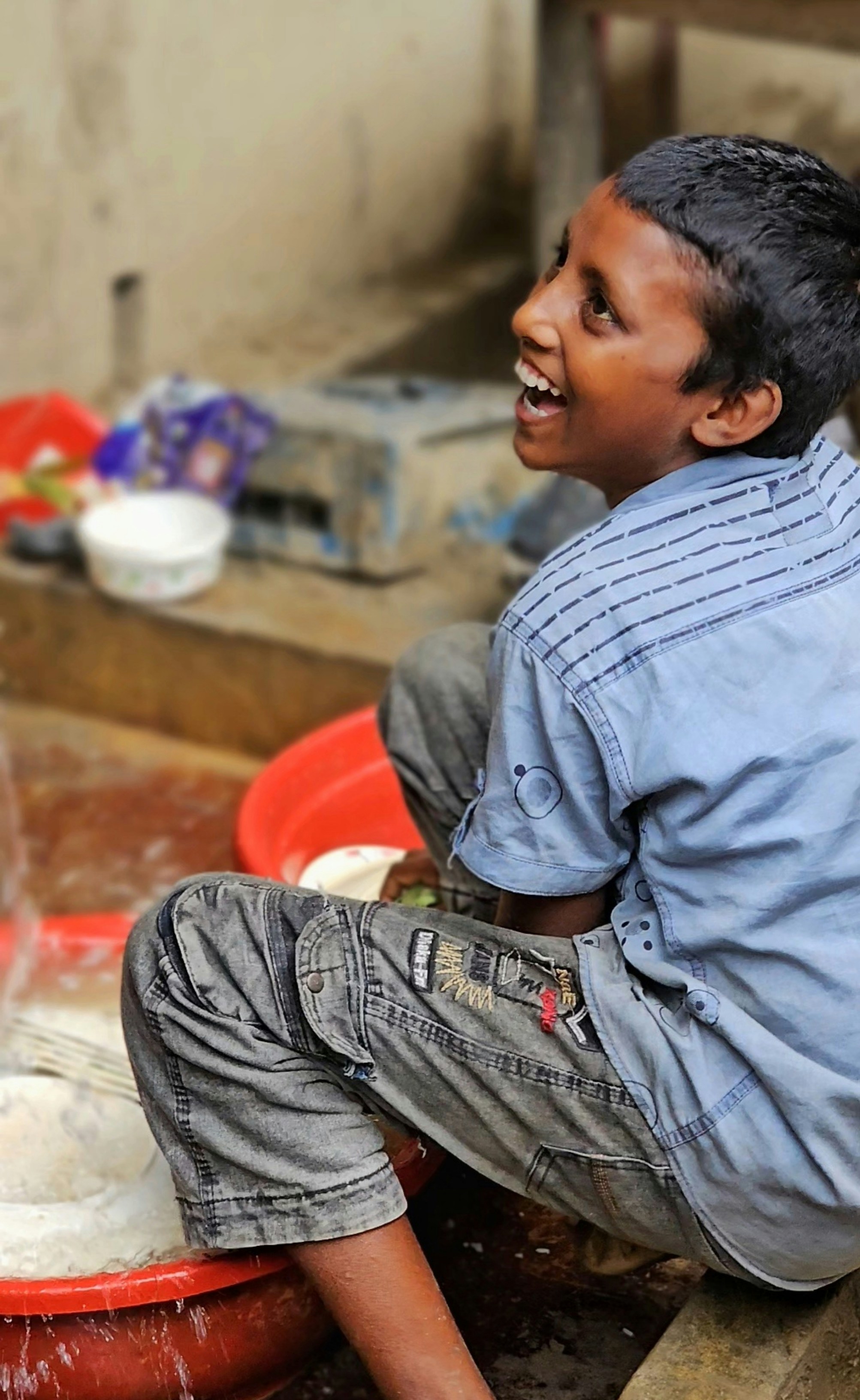 A young boy sitting on a red bucket