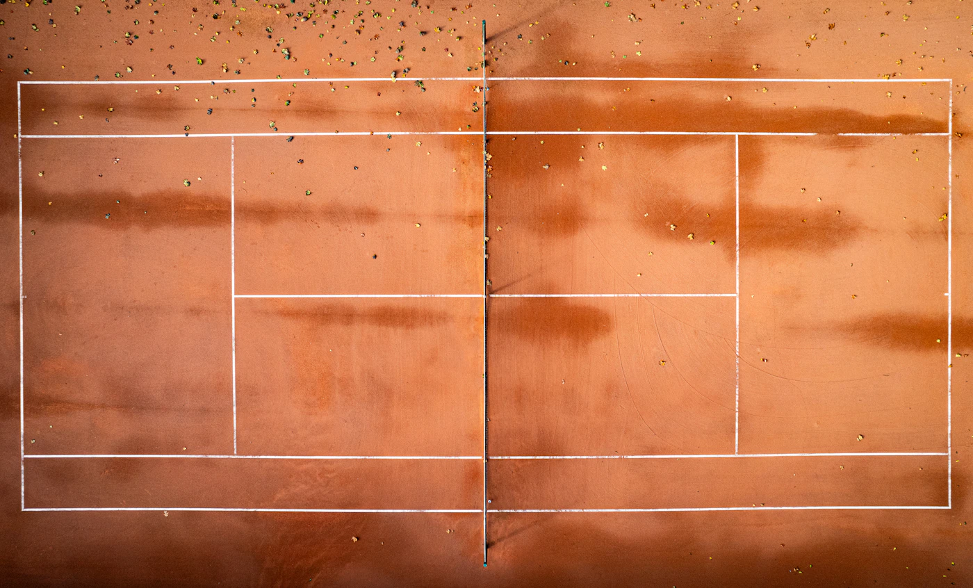 Shadow of a tennis player cast on a clay court