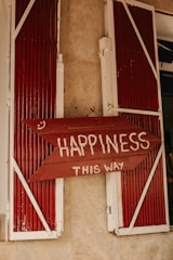 A red sign that says happiness is in front of a window