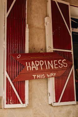 A red sign that says happiness is in front of a window