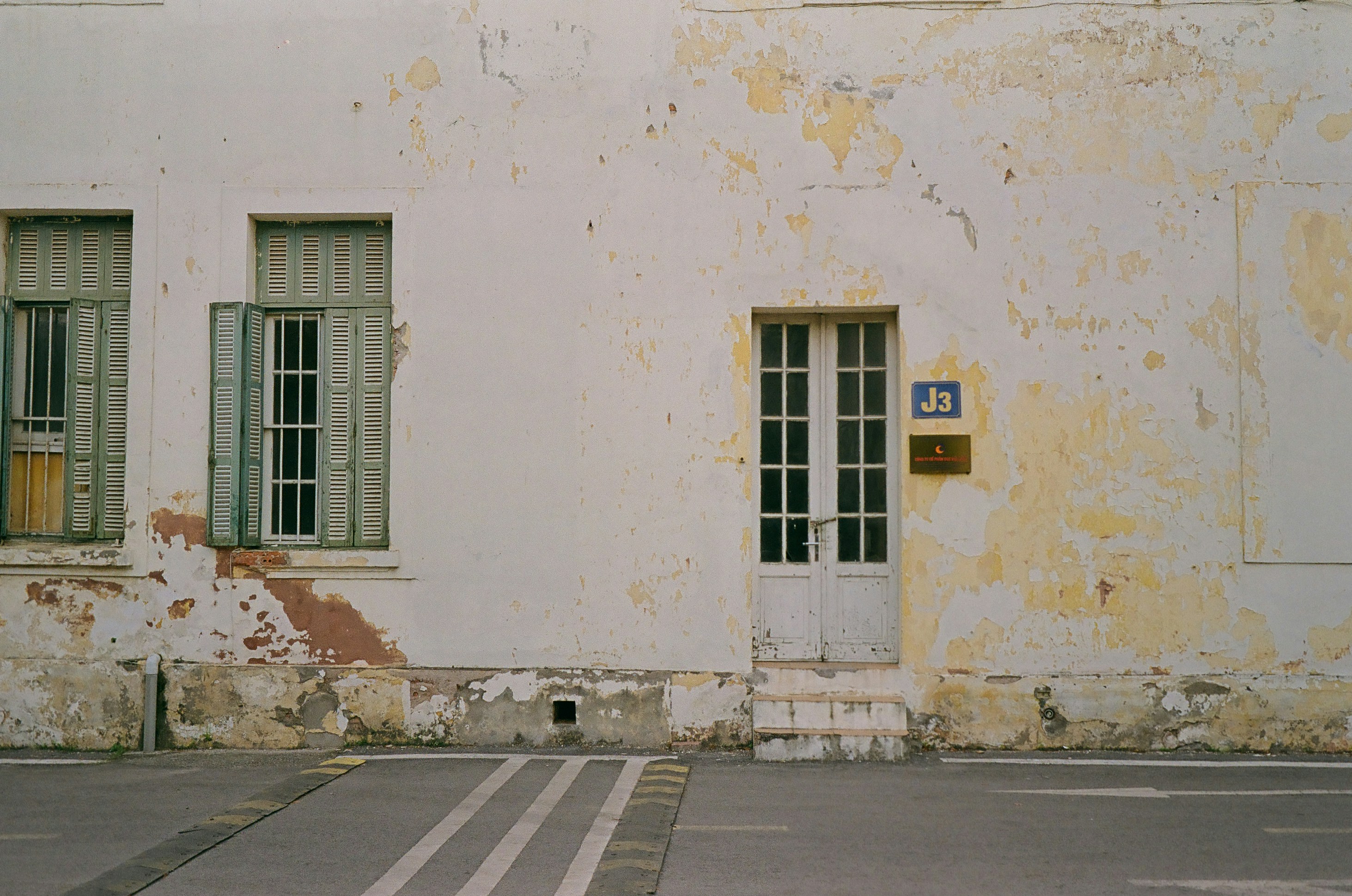 Un edificio blanco con dos ventanas y un letrero frente a él
