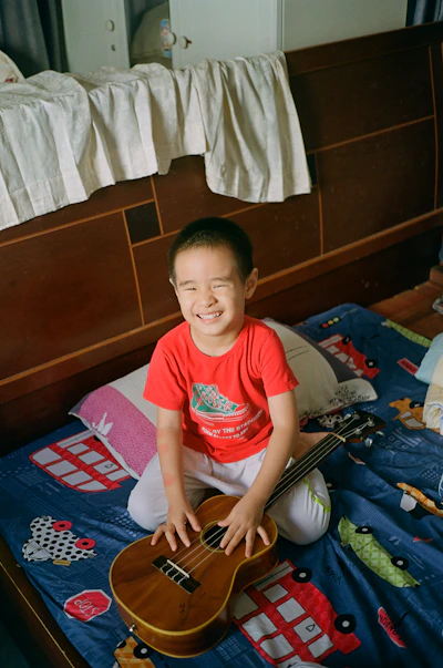 A little girl sitting on a bed with a guitar