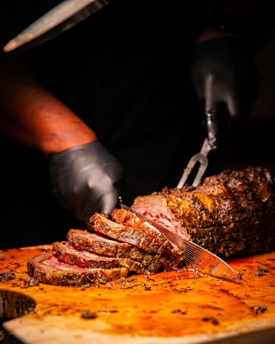 A person cutting a large piece of meat on a cutting board