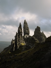 A group of rocks on a hill with a cloudy sky in the background