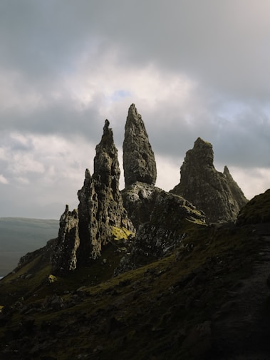 A group of rocks on a hill with a cloudy sky in the background