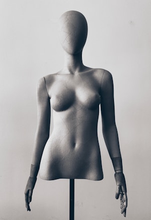 A mannequin is standing on a wooden stand