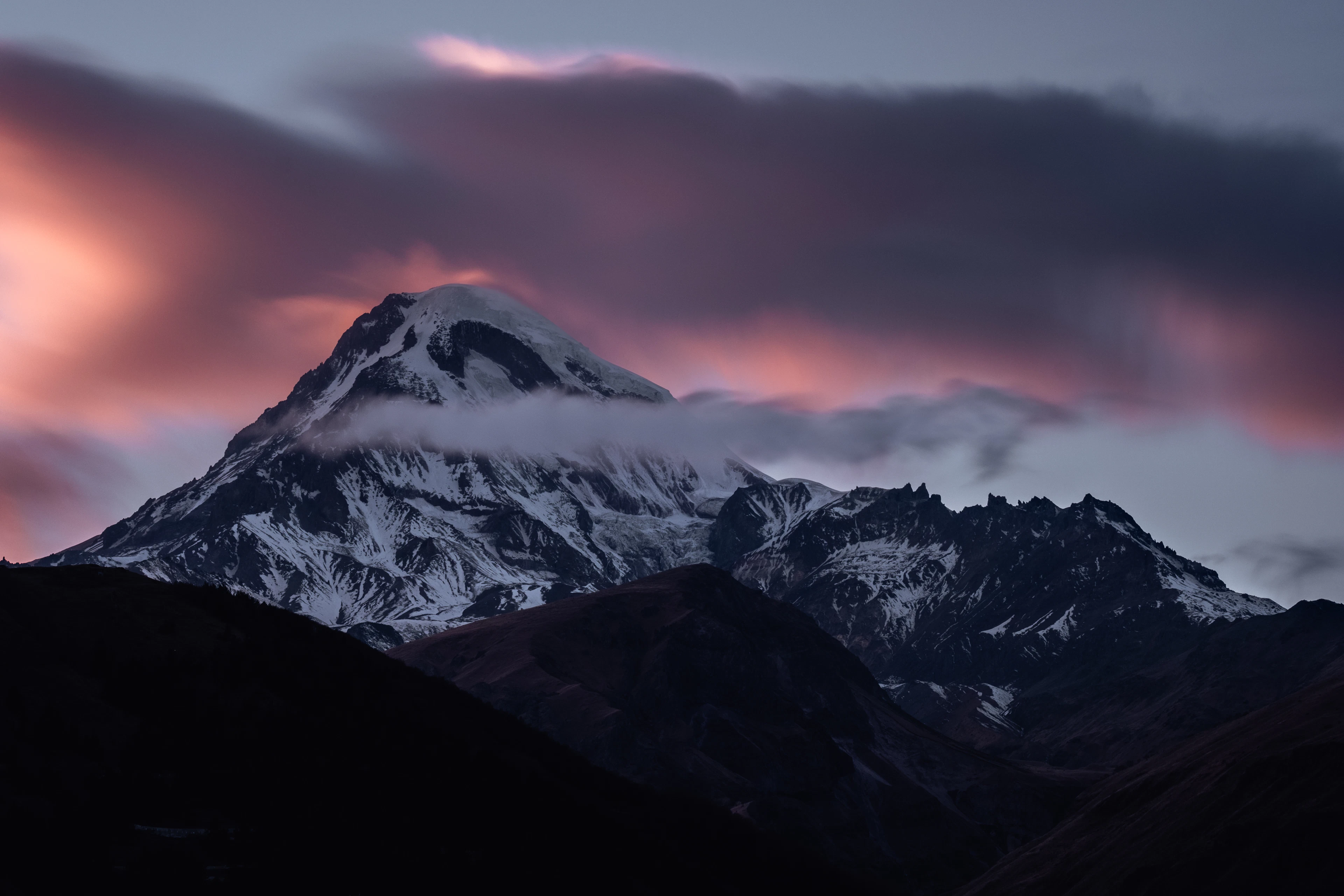 Snow peak of the Caucasus glowing pink at sunset in Kazbegi, Georgia