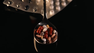 A spoon filled with lots of pills on top of a table