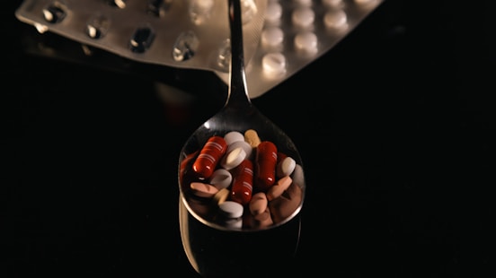 A spoon filled with lots of pills on top of a table
