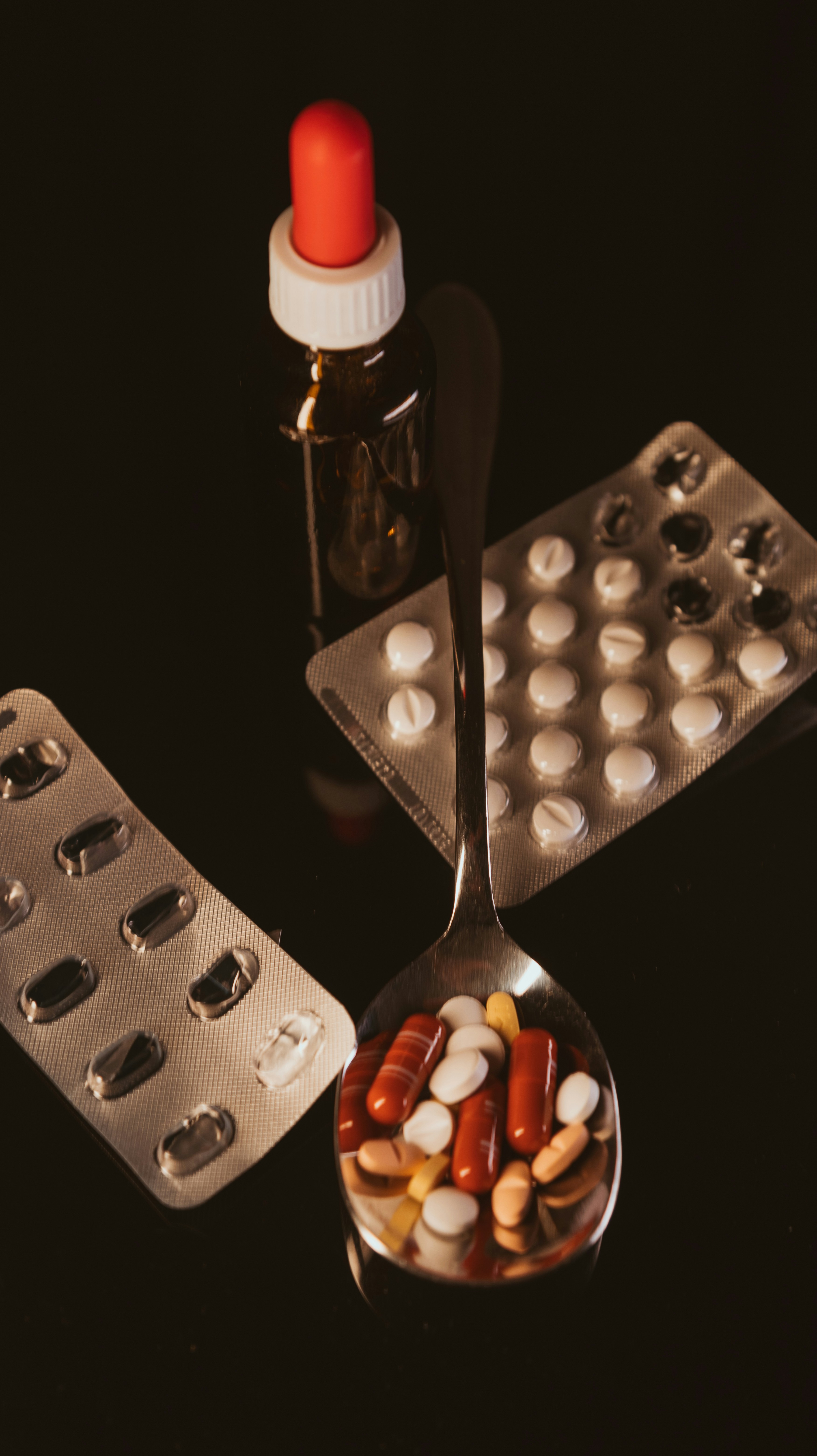 A spoon with pills and a bottle of pills