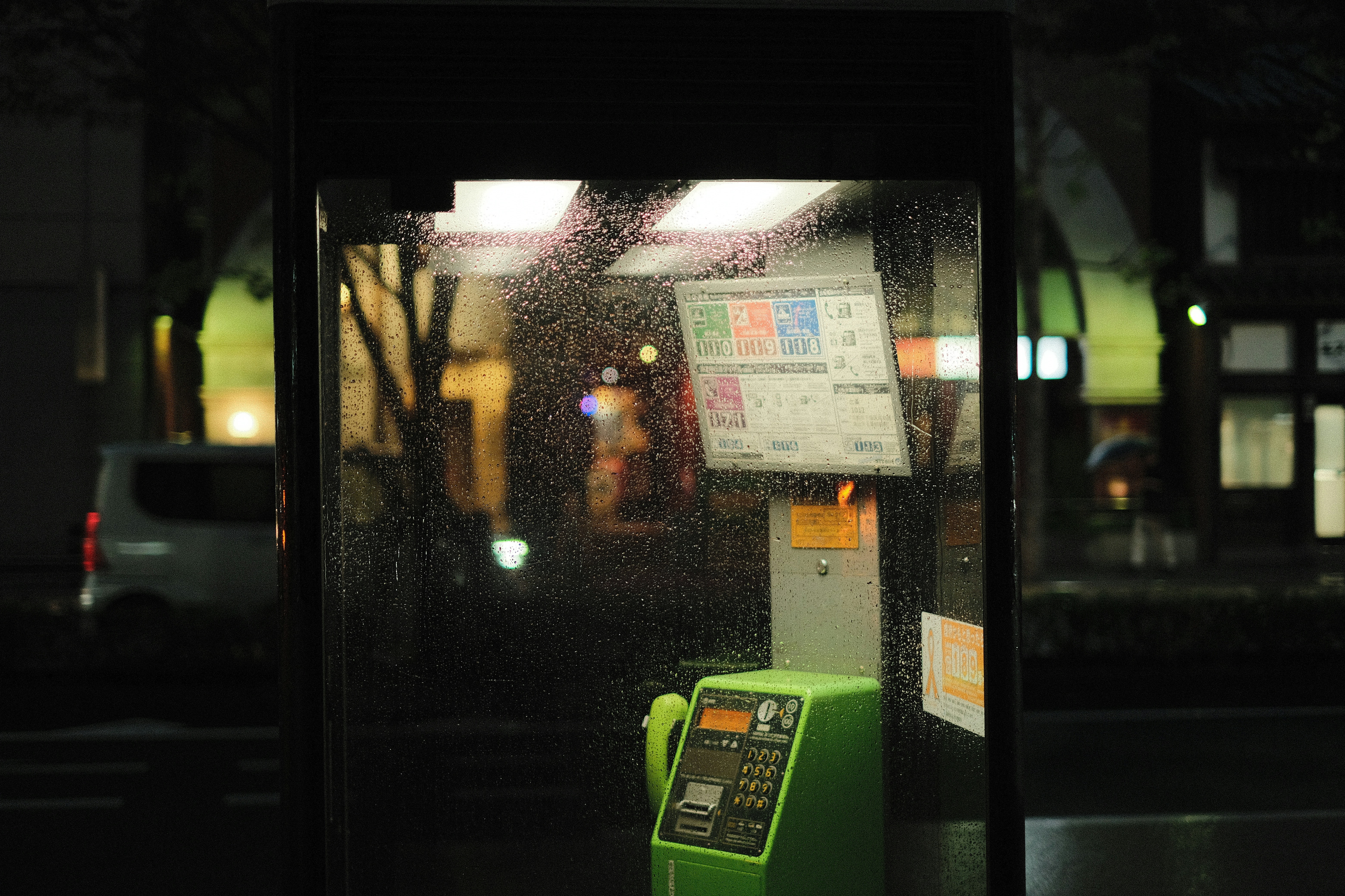 A green phone sitting on the side of a bus stop