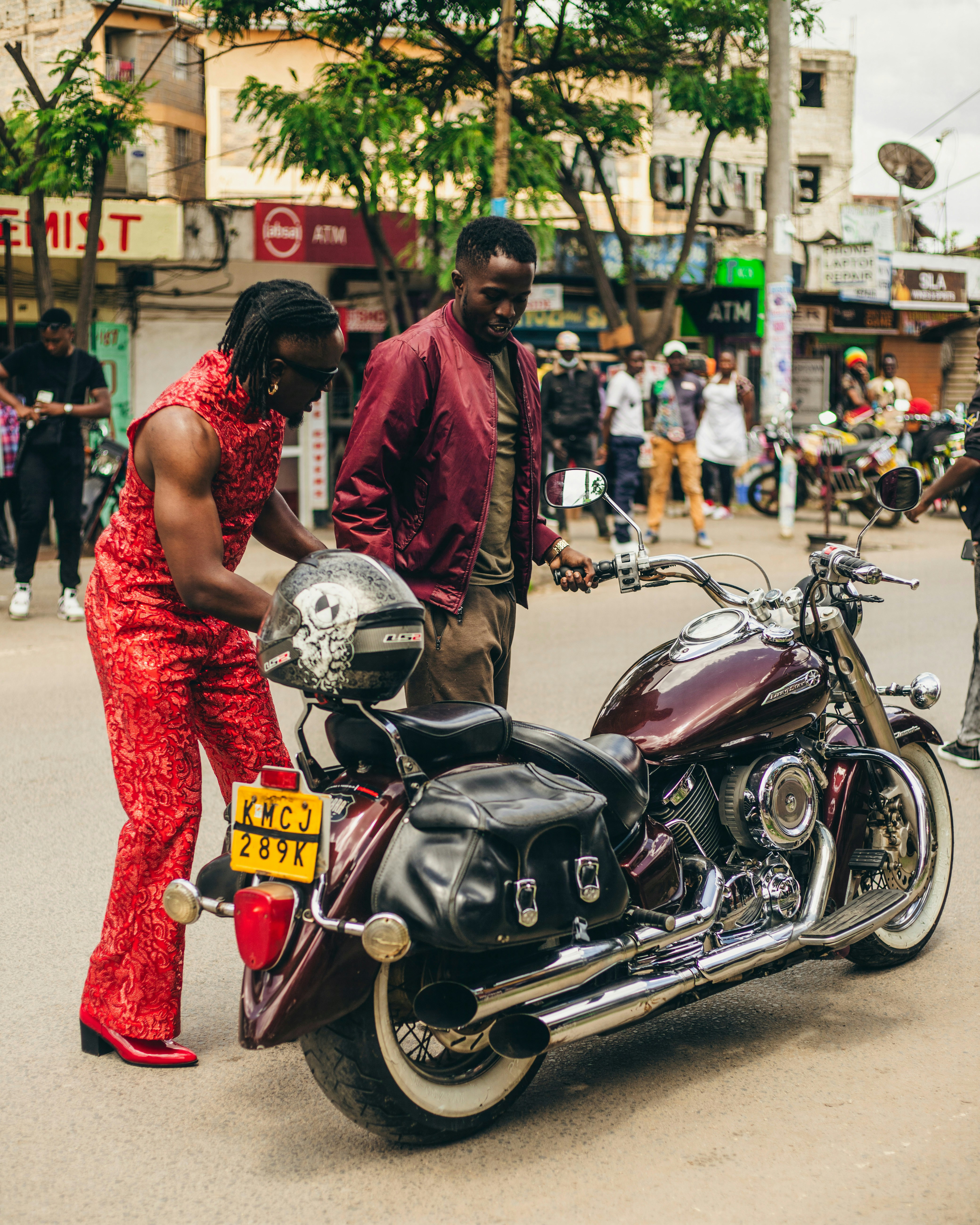 Un homme debout à côté d’une moto dans une rue
