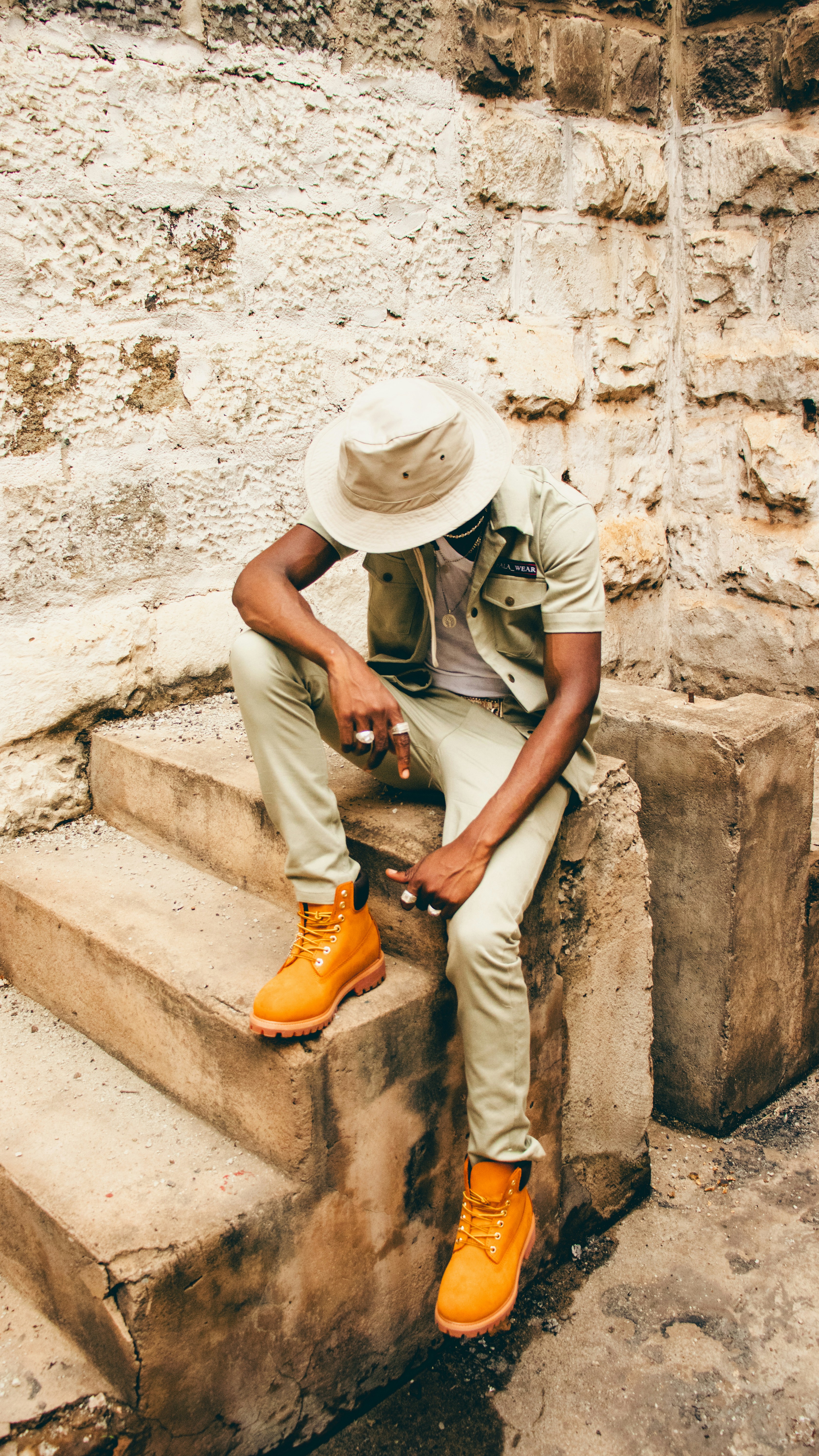 A man sitting on a stone step with a hat on