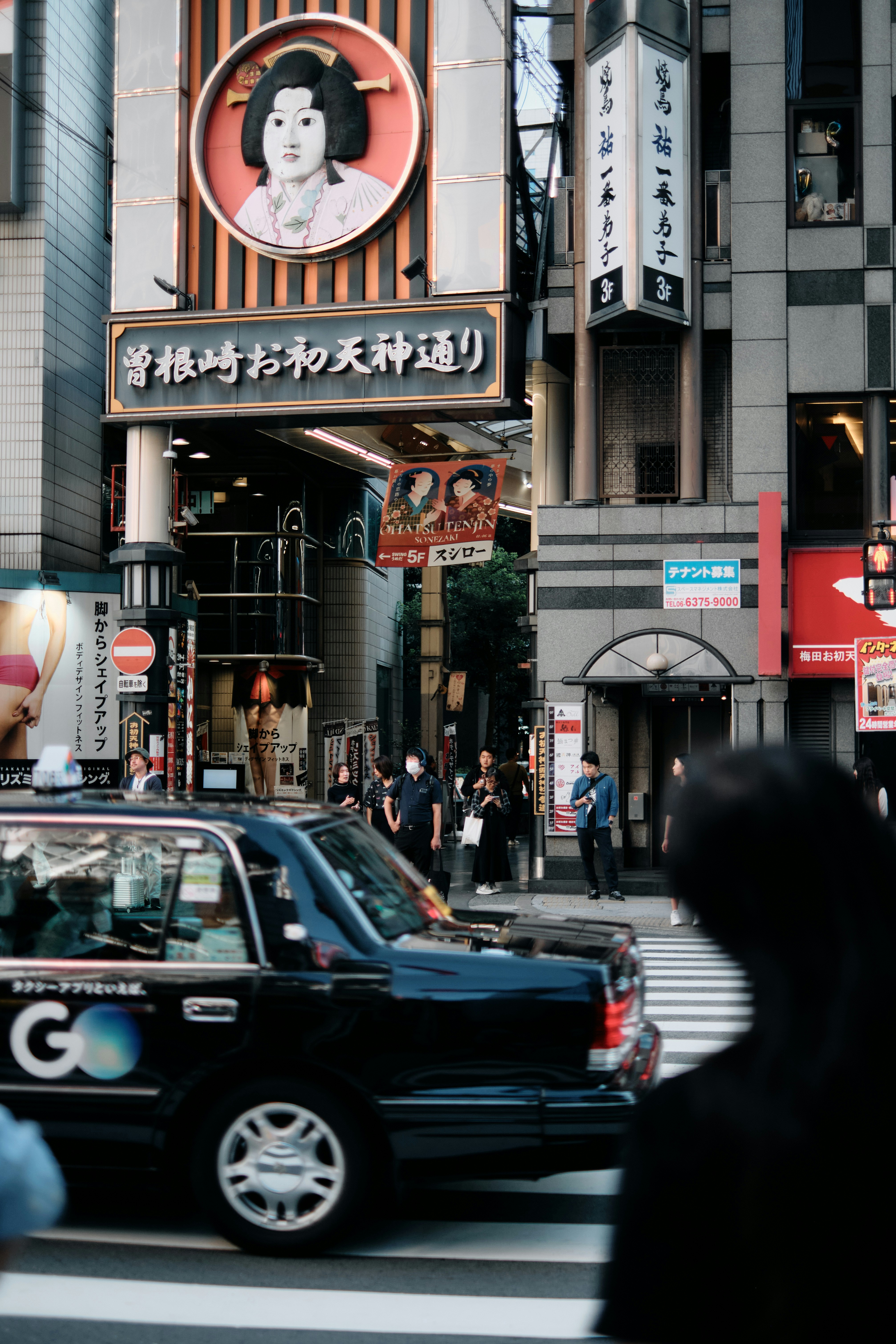 A taxi cab driving down a street next to tall buildings