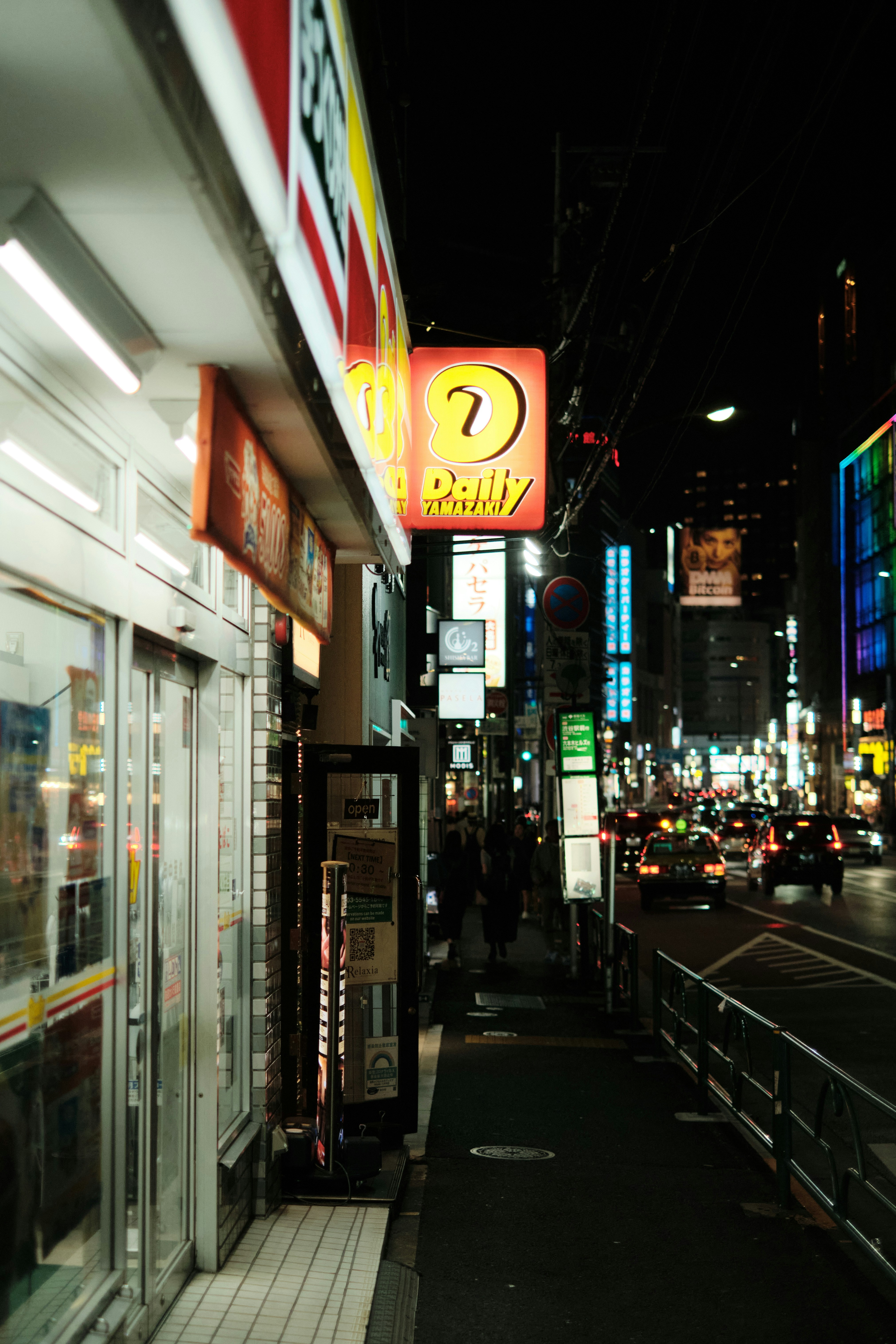 A city street at night with neon signs