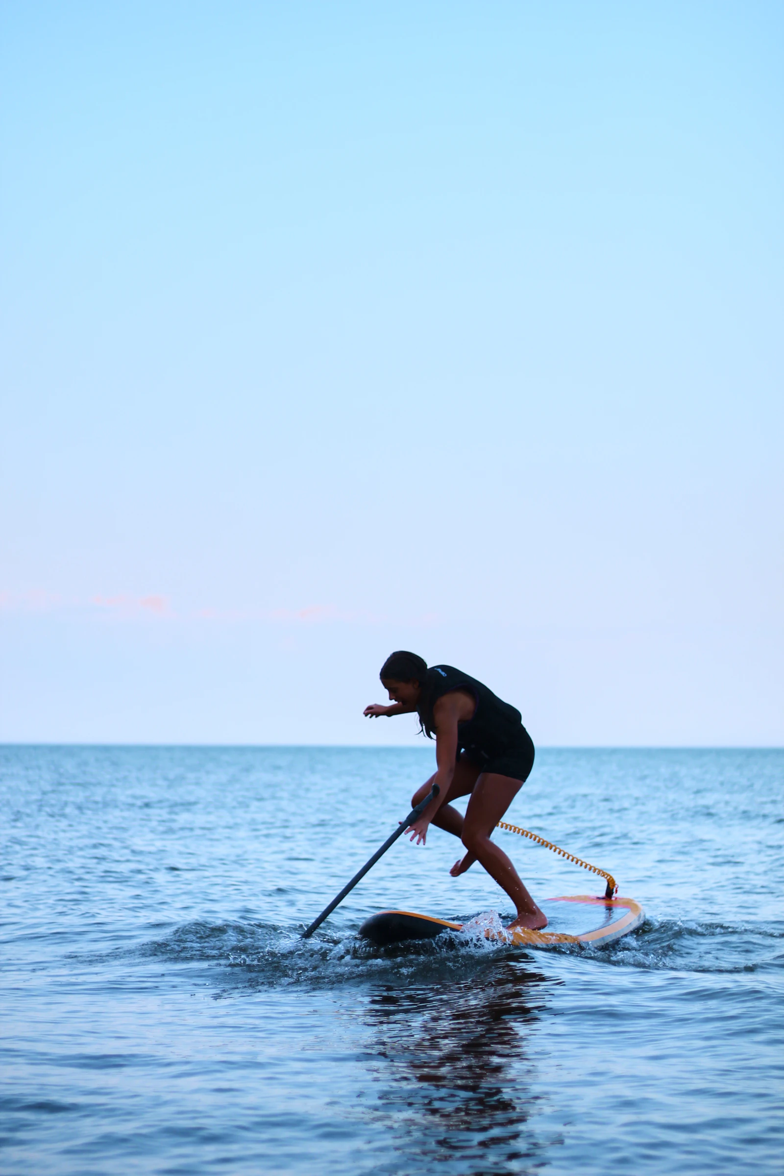 Paddle boarder moving across open water with a paddle