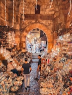 Two men walking through a market filled with lots of items