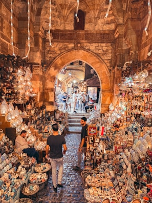 Two men walking through a market filled with lots of items