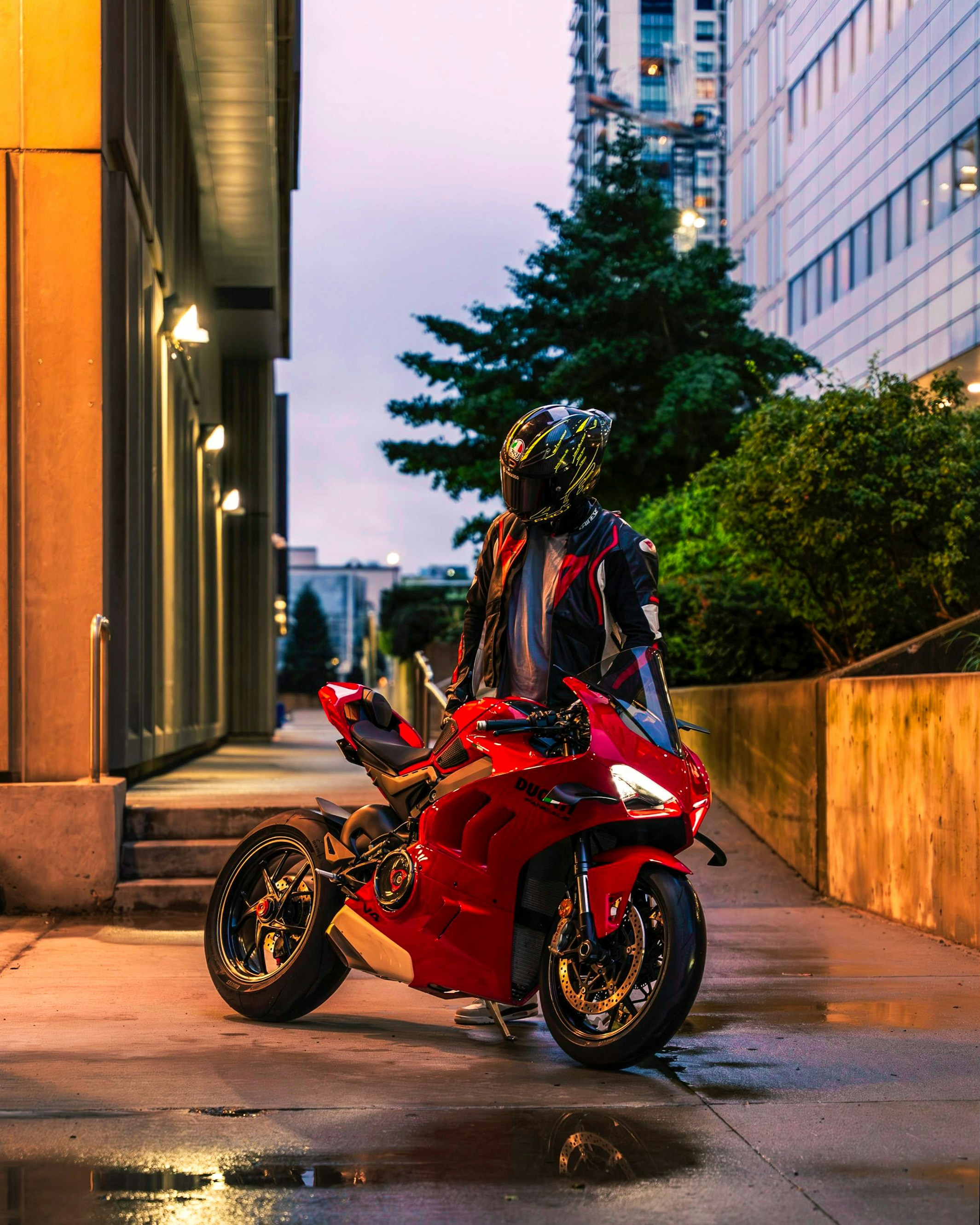 A man standing next to a red motorcycle on a city street