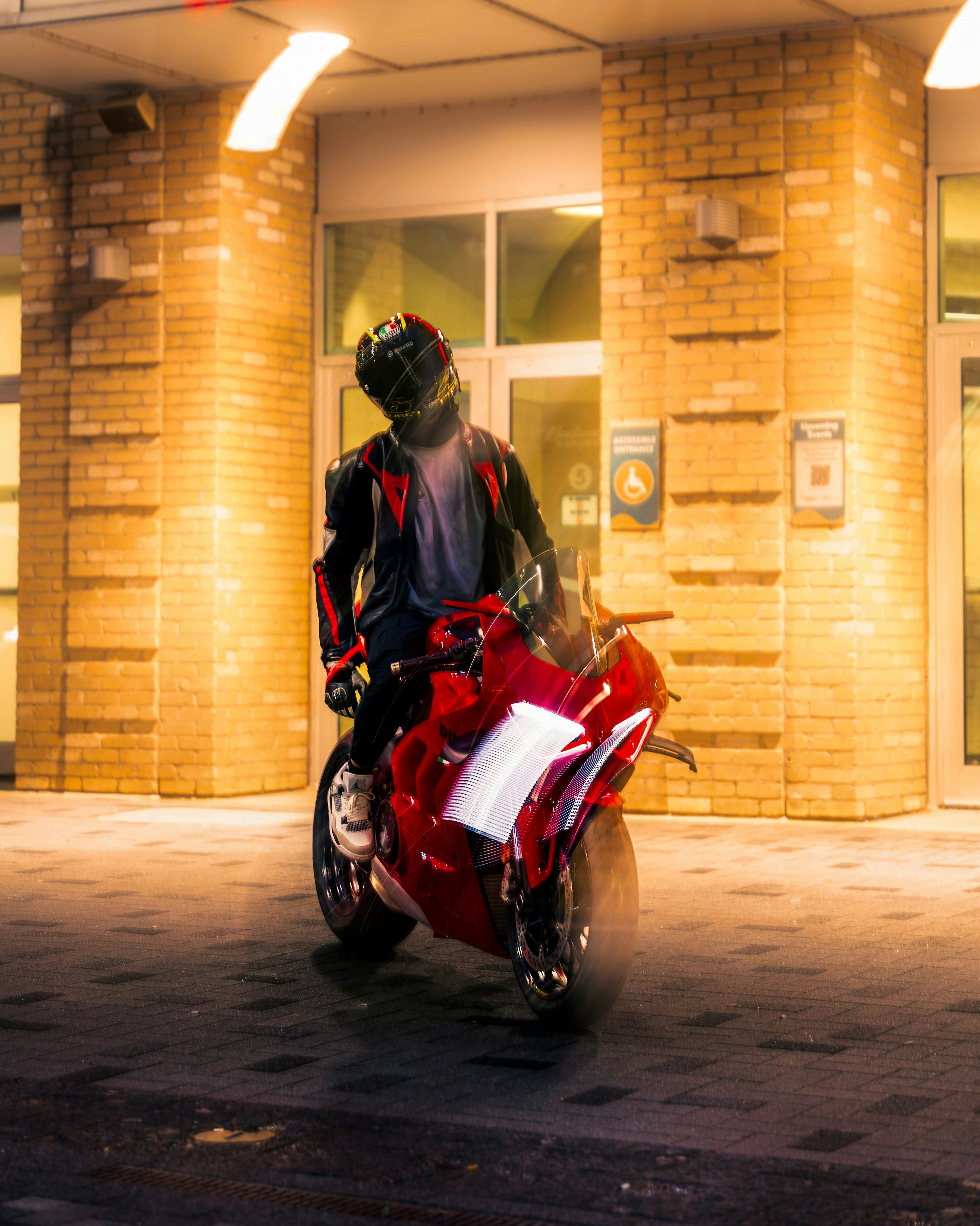A person on a red motorcycle in front of a building