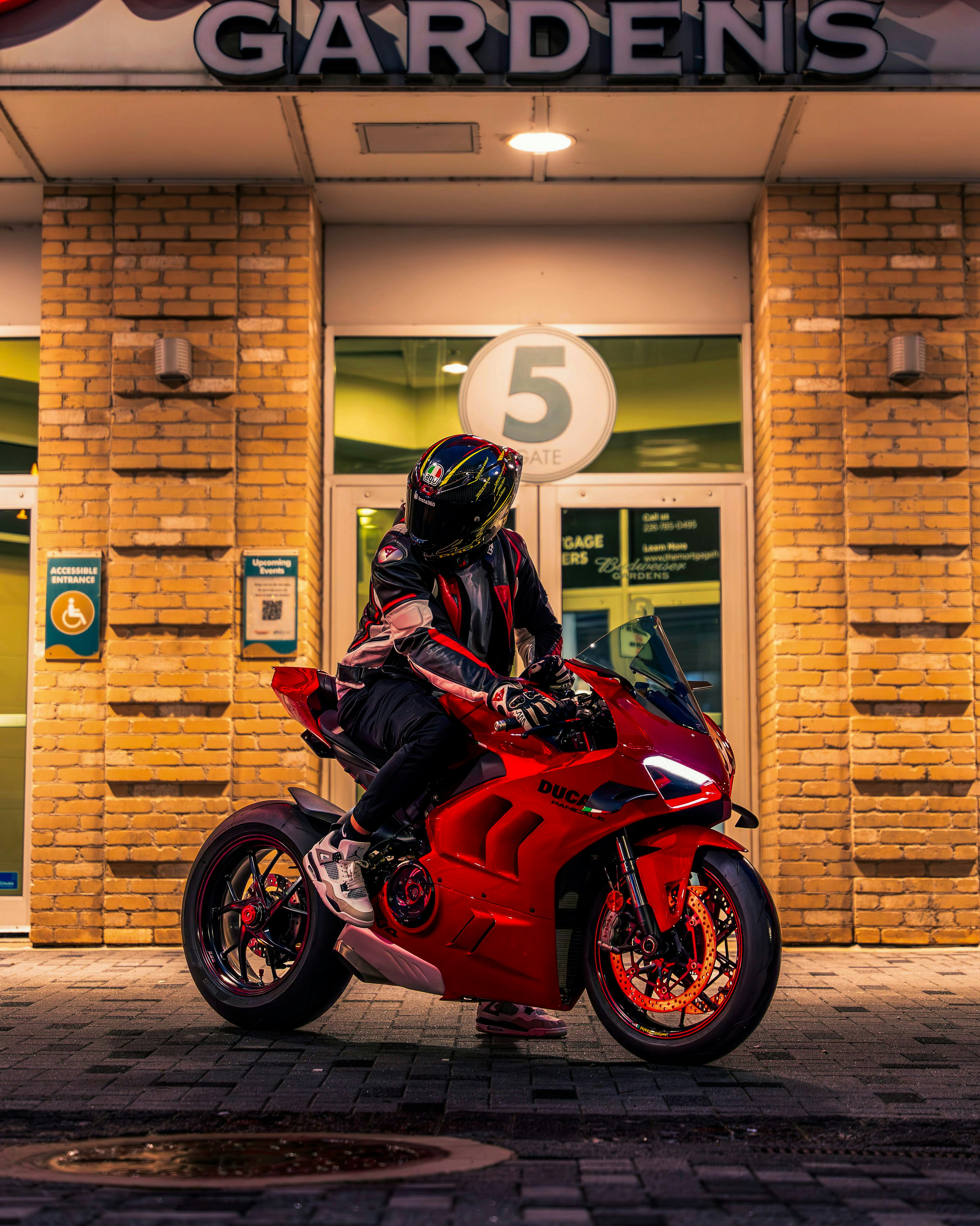 A person on a red motorcycle in front of a building