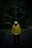 A person in a yellow raincoat standing in the dark