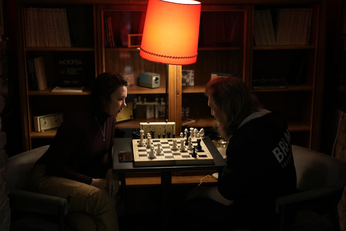Two chess players competing across a board in a dimly lit room