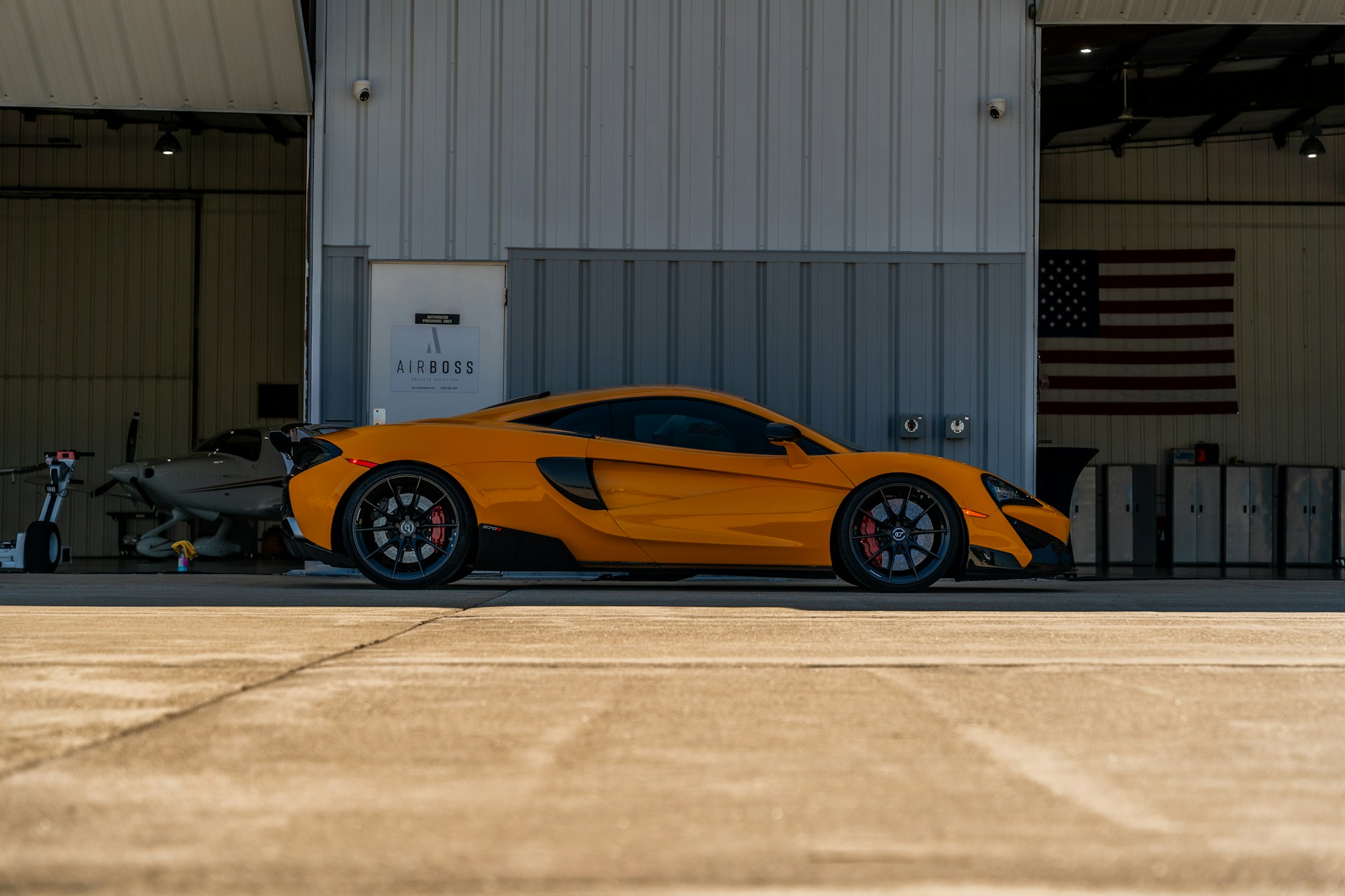 An orange sports car parked in front of a hangar