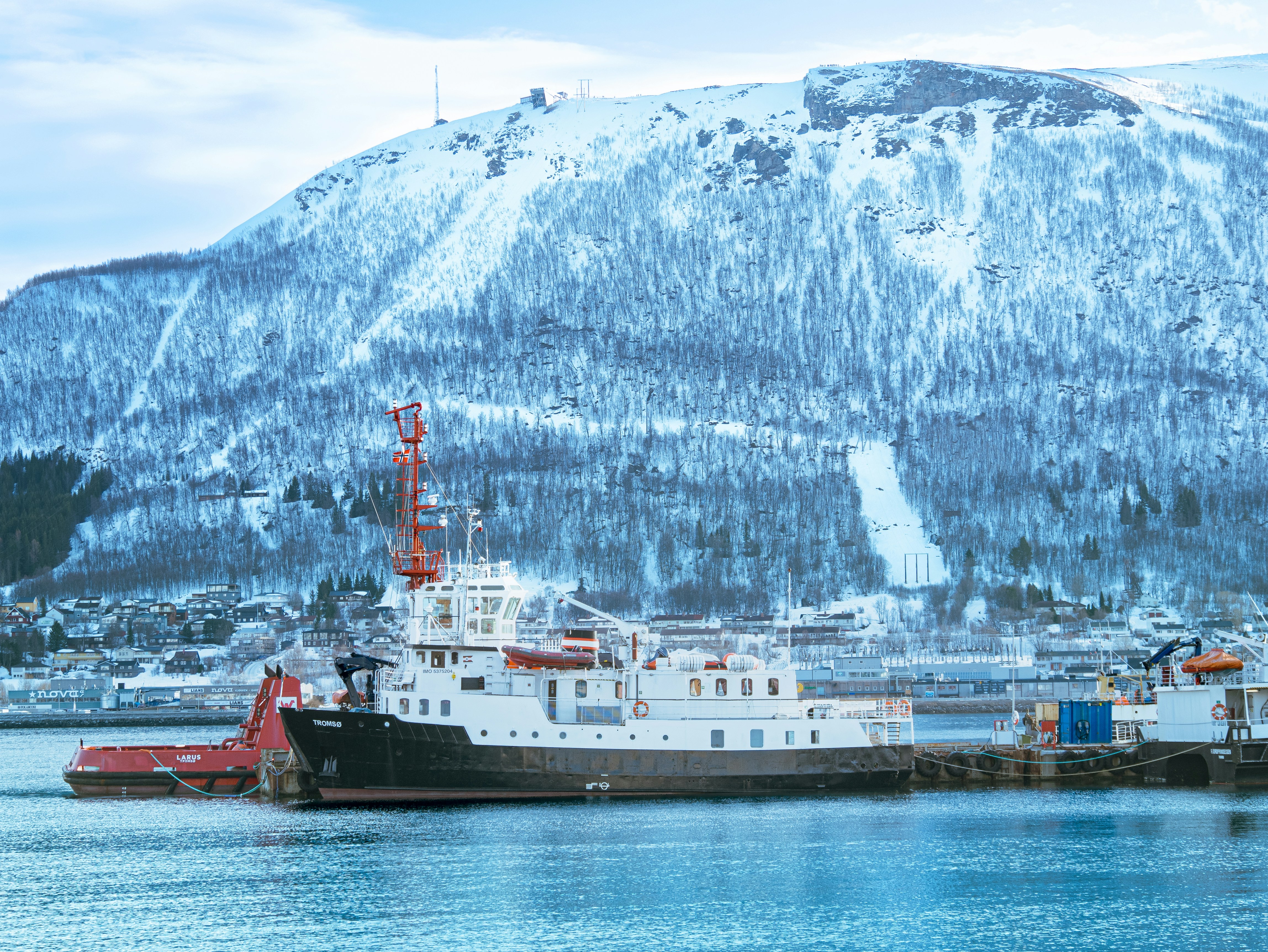 A boat docked in a harbor with a mountain in the background