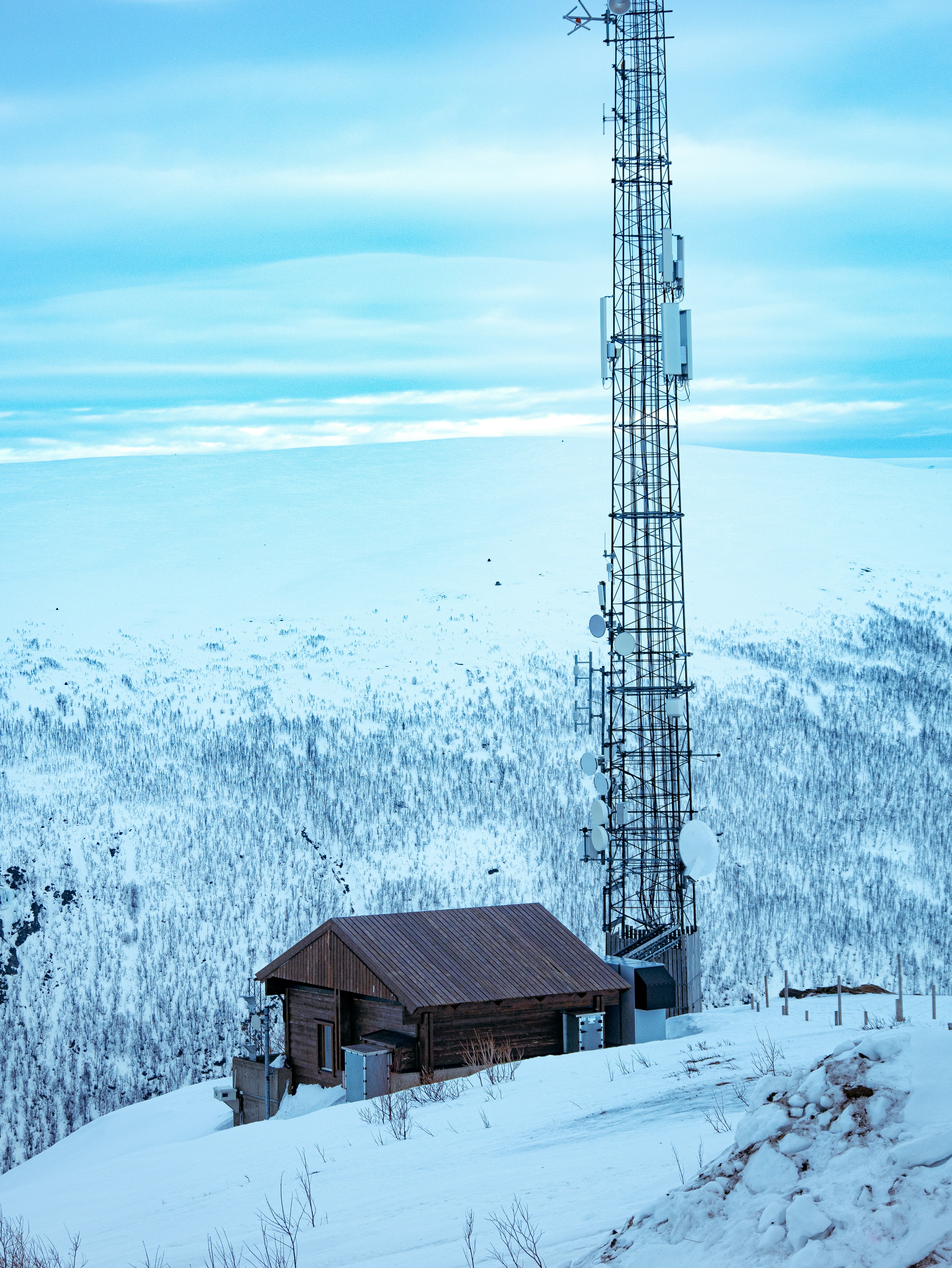 A radio tower sitting on top of a snow covered hill
