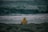 A person in a yellow jacket sitting on a beach