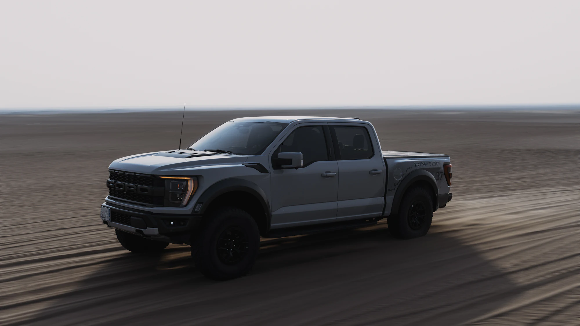Gray Ford F-150 Raptor driving across sand flats at dusk