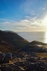 The sun is shining over the ocean on a rocky shore