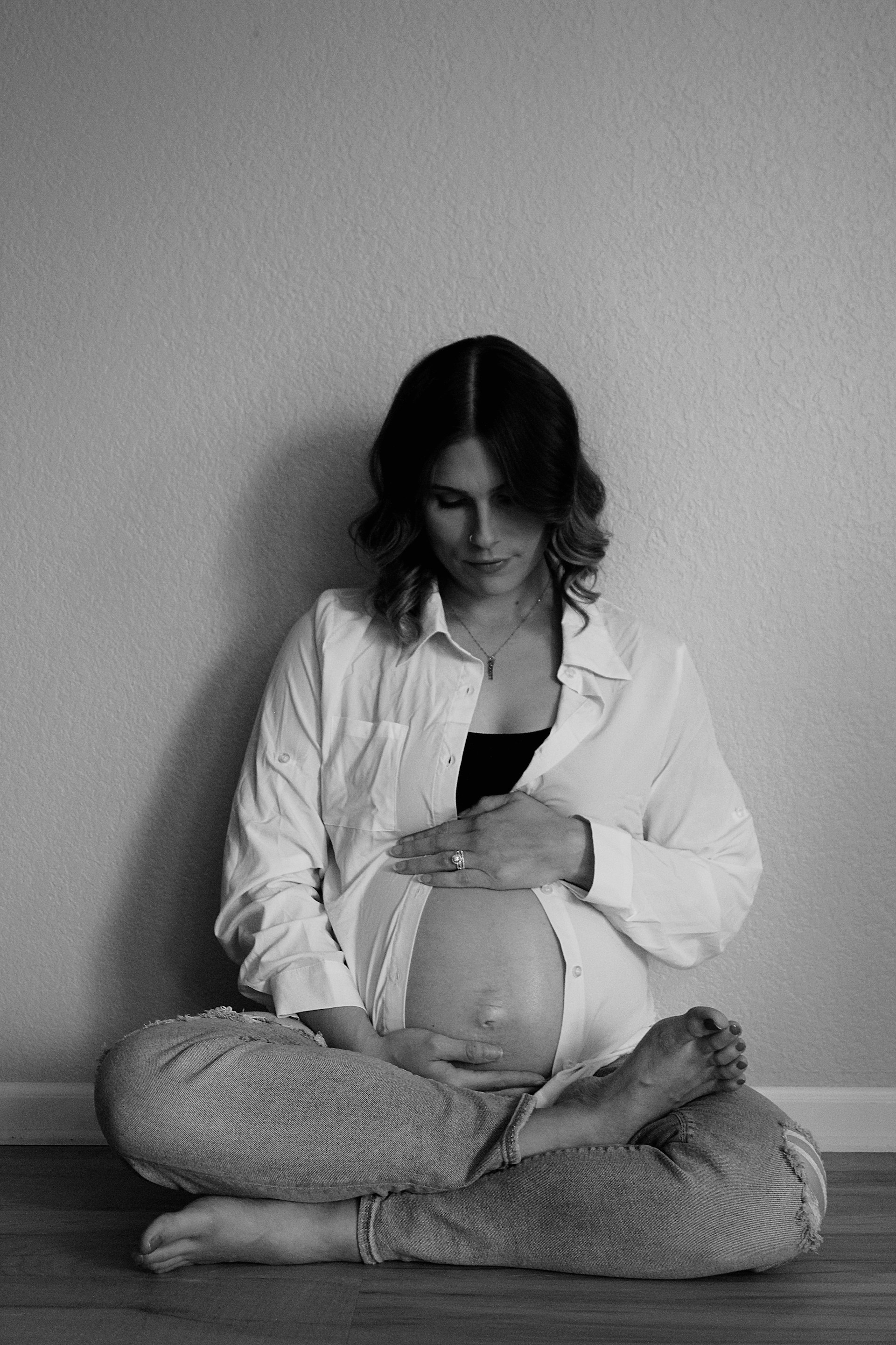 A pregnant woman sitting on the floor with her belly exposed