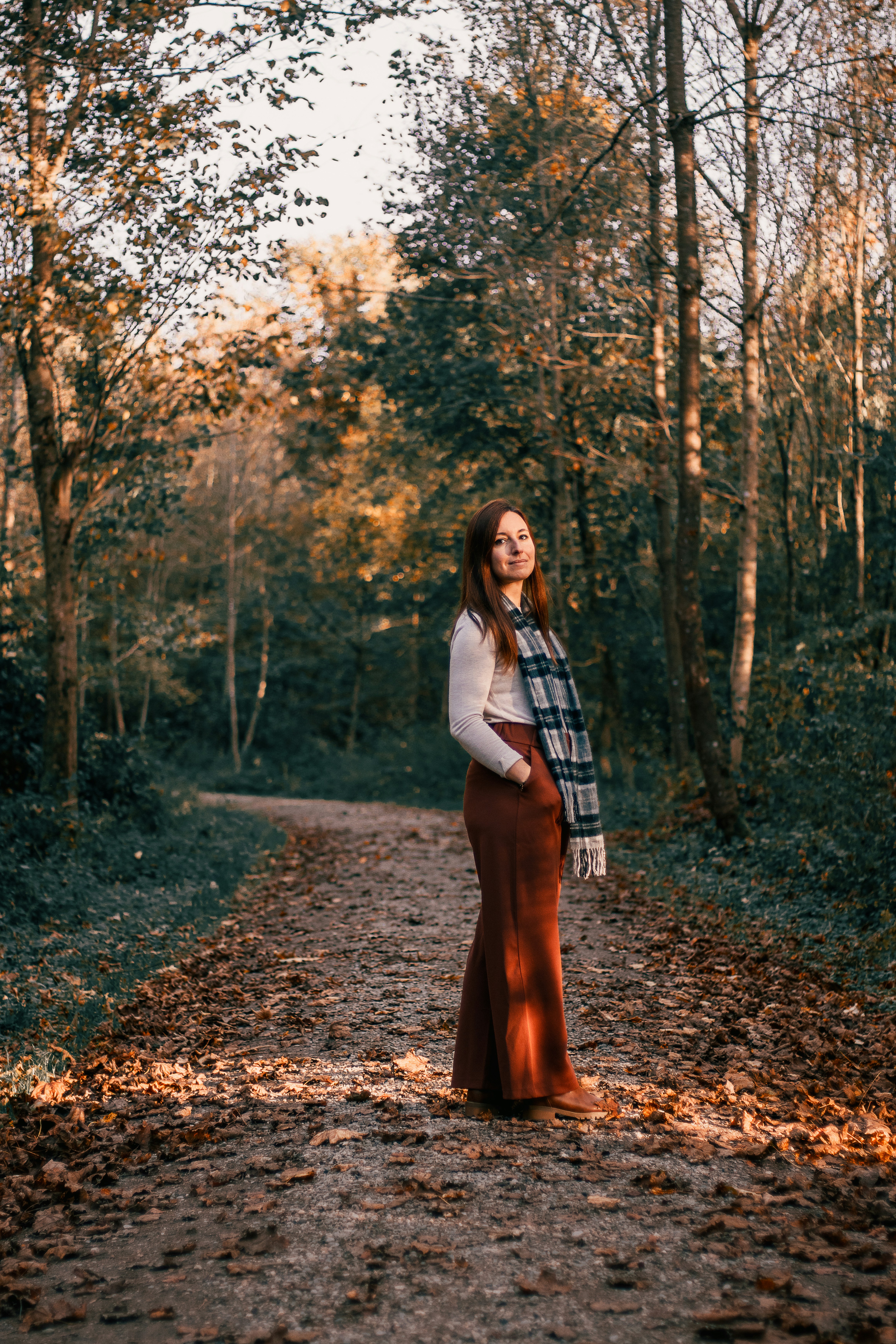 A woman standing on a dirt road in the woods