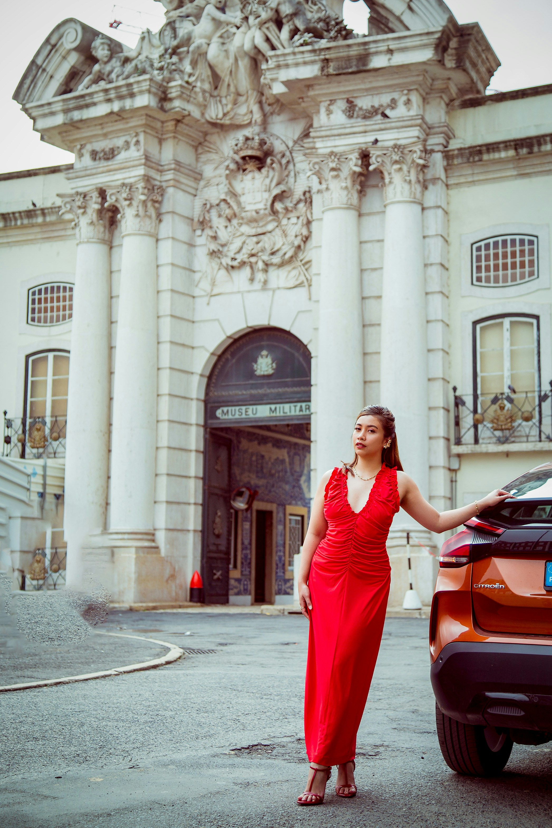 A woman standing next to a car in front of a building